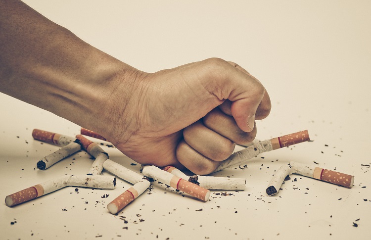Moška roka uničuje cigarete, vapiranje lahko pomaga pri opuščanju kajenja