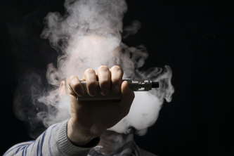 Fordampning af tobak, hånd med vaporizer på sort baggrund